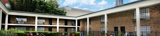 Apartments near the Galleria with multiple swimming pools, sun deck with poolside lounge chairs, brick exteriors and courtyard setting at Plantation apartments in Houston.