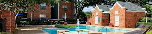Luxury apartments with two swimming pools with fountain, poolside lounge chairs, and beautiful landscaping in Dallas