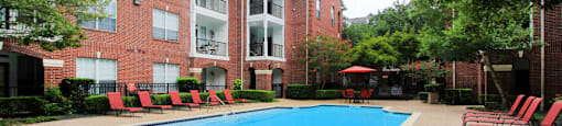 Luxury swimming pool with spacious sundeck, beautiful landscaping, and poolside lounge seating at Tuscany Oaks Apartments in Houston.