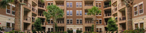 Luxury apartments with resort-style pool, palm trees, spacious sundeck with poolside lounge chairs, grilling station, fountains, and fitness center at Villa Piana Apartments in Dallas