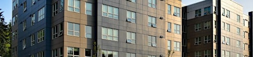A modern multi-story building with a mix of dark and light brown panels.