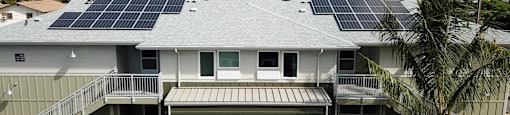 A house with solar panels on the roof and a mountain range in the background.