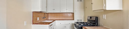 A kitchen with white cabinets and a wooden countertop.