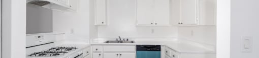 A kitchen with white cabinets and a blue trash can.