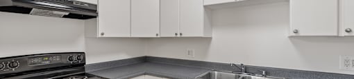 A kitchen with white cabinets and a black stove top oven.