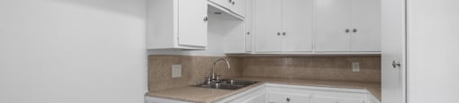 a kitchen with white cabinets and white appliances and a sink