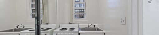 a white kitchen with white appliances and a window and a mirror