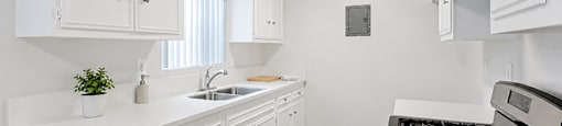A kitchen with white cabinets and a black stove top oven.
