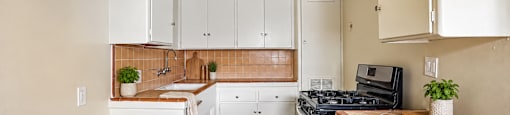 A kitchen with white cabinets and a black stove top oven.