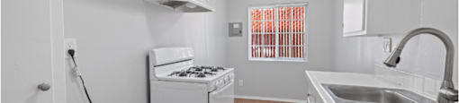 a kitchen with a stove and a sink and a ceiling fan
