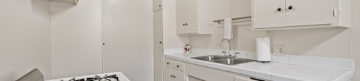 a kitchen with white cabinets and a stove and a sink