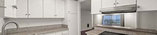 A kitchen with a stove, sink, and cabinets.