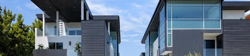 a row of modern houses with black facade and a blue sky