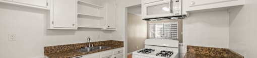 A kitchen with white cabinets and a brown countertop.