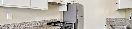 A kitchen with white cabinets and a granite countertop.