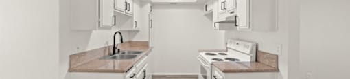 A kitchen with white cabinets and a wooden floor.