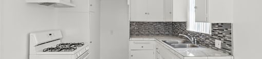 A kitchen with white cabinets and a wooden floor.