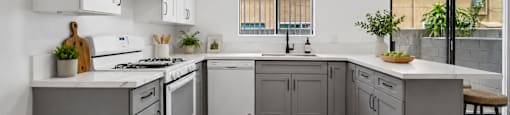 A modern kitchen with white cabinets and a wooden floor.