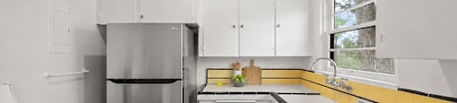 A kitchen with white cabinets and a yellow stripe on the wall.