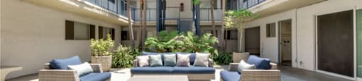 a patio area with couches and tables in a courtyard
