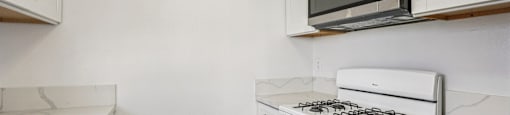 A white kitchen with a black microwave above the stove.