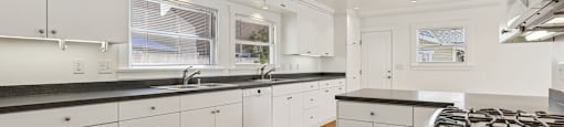 A modern kitchen with white cabinets and a black countertop.