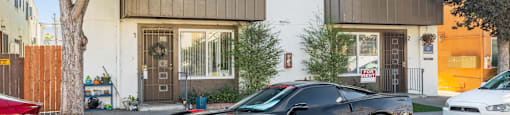 A black sports car is parked in front of a two-story building.