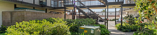 A green container is on the ground next to a concrete path.