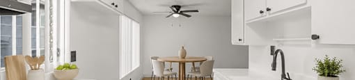 A modern kitchen with white cabinets and a dining table.