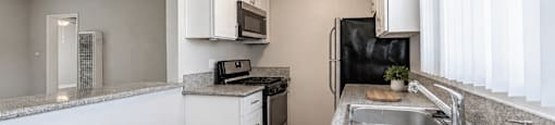 A kitchen with a sink, stove, and cabinets.