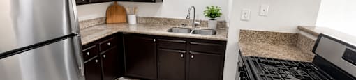 A kitchen with a refrigerator, sink, and cabinets.