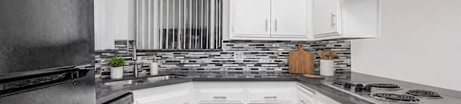 A kitchen with white cabinets and a black refrigerator.