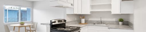 A kitchen with white cabinets and a black stove top oven.