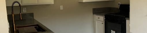 A kitchen with white cabinets and a black stove top oven.