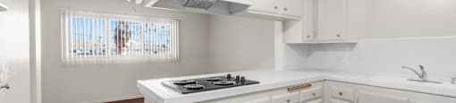 A white kitchen with wood floors and a window.