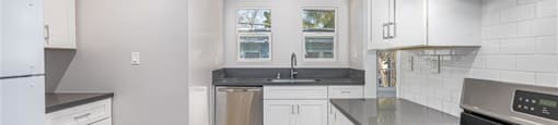 A kitchen with white cabinets and a black stove top.