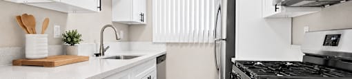 A kitchen with white cabinets and a black stove top.