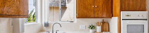 A kitchen with wooden cabinets and a white oven.