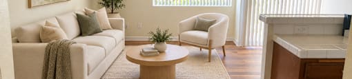 A living room with a white couch, a coffee table, and a painting on the wall.