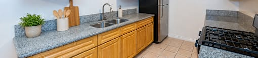 A kitchen with wooden cabinets and a black fridge.