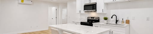 A kitchen with white cabinets and a wooden floor.
