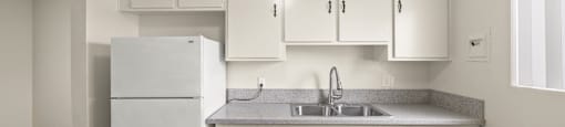 A kitchen with white cabinets and a refrigerator.