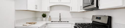 A kitchen with white cabinets and a black stove top oven.