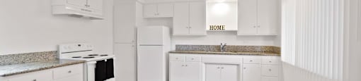 A kitchen with white cabinets and a wooden floor.