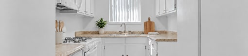 A kitchen with white cabinets and a wooden floor.