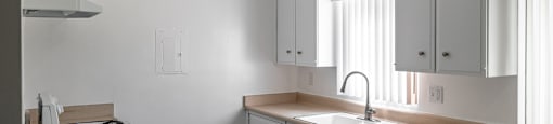 A kitchen with white cabinets and a stove top oven.