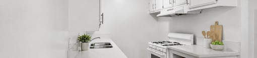 A kitchen with white cabinets and appliances, with the logo of Beach Front Property Management in the bottom left corner.