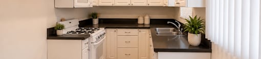 A kitchen with white cabinets and black countertops.