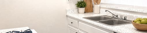 A kitchen with a white stove top and white cabinets.