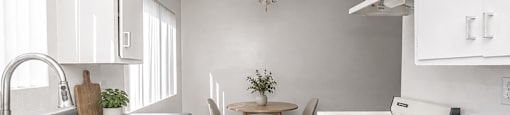 A kitchen with white cabinets and a wooden table.